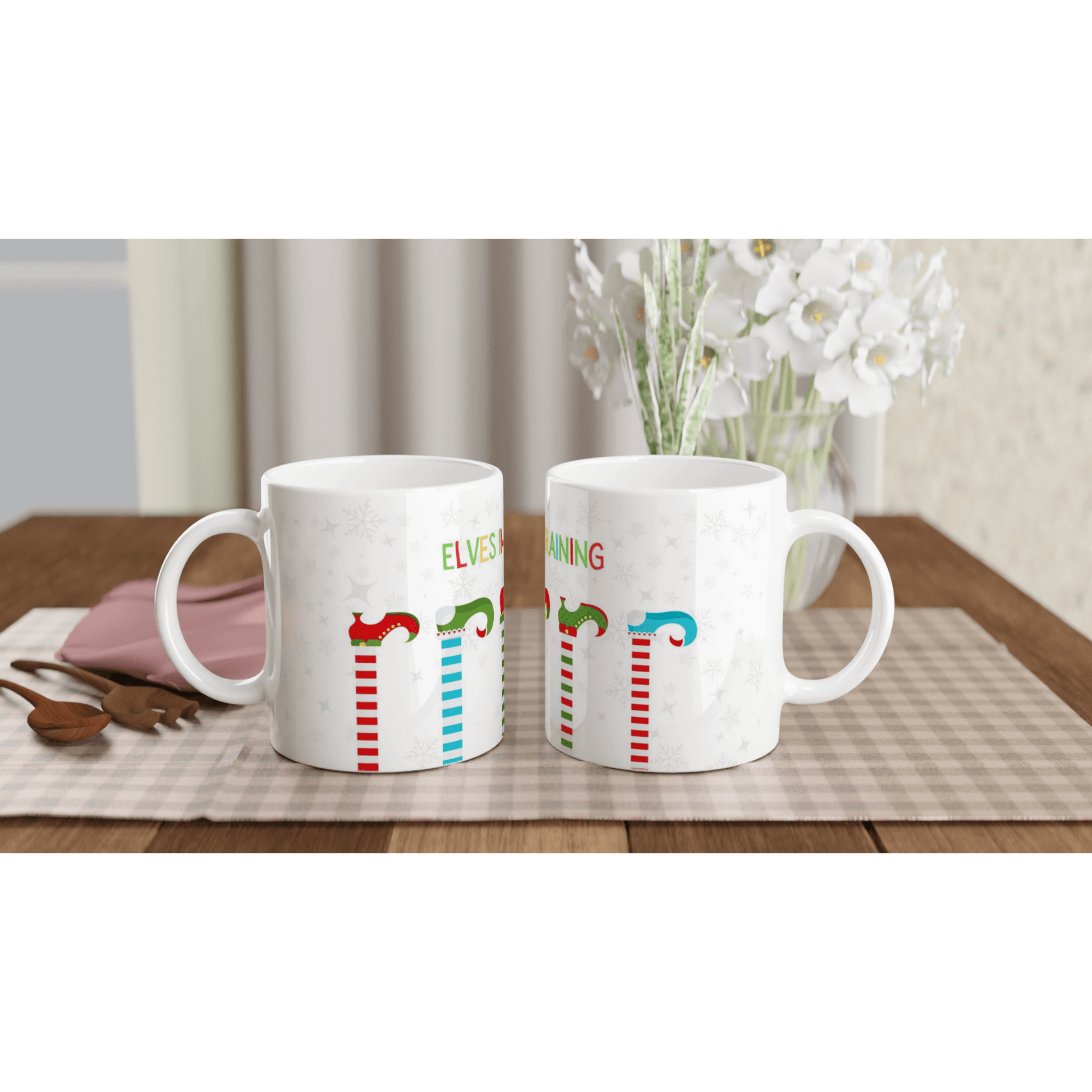 white mugs with colorful designs of elves on it with the text, 'elves in training'.