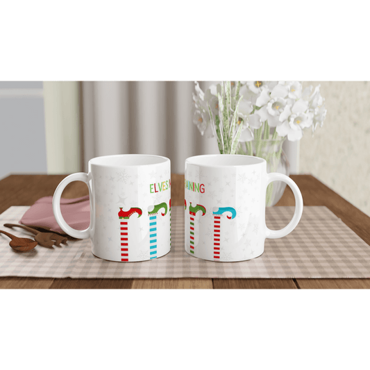 white mugs with colorful designs of elves on it with the text, 'elves in training'.